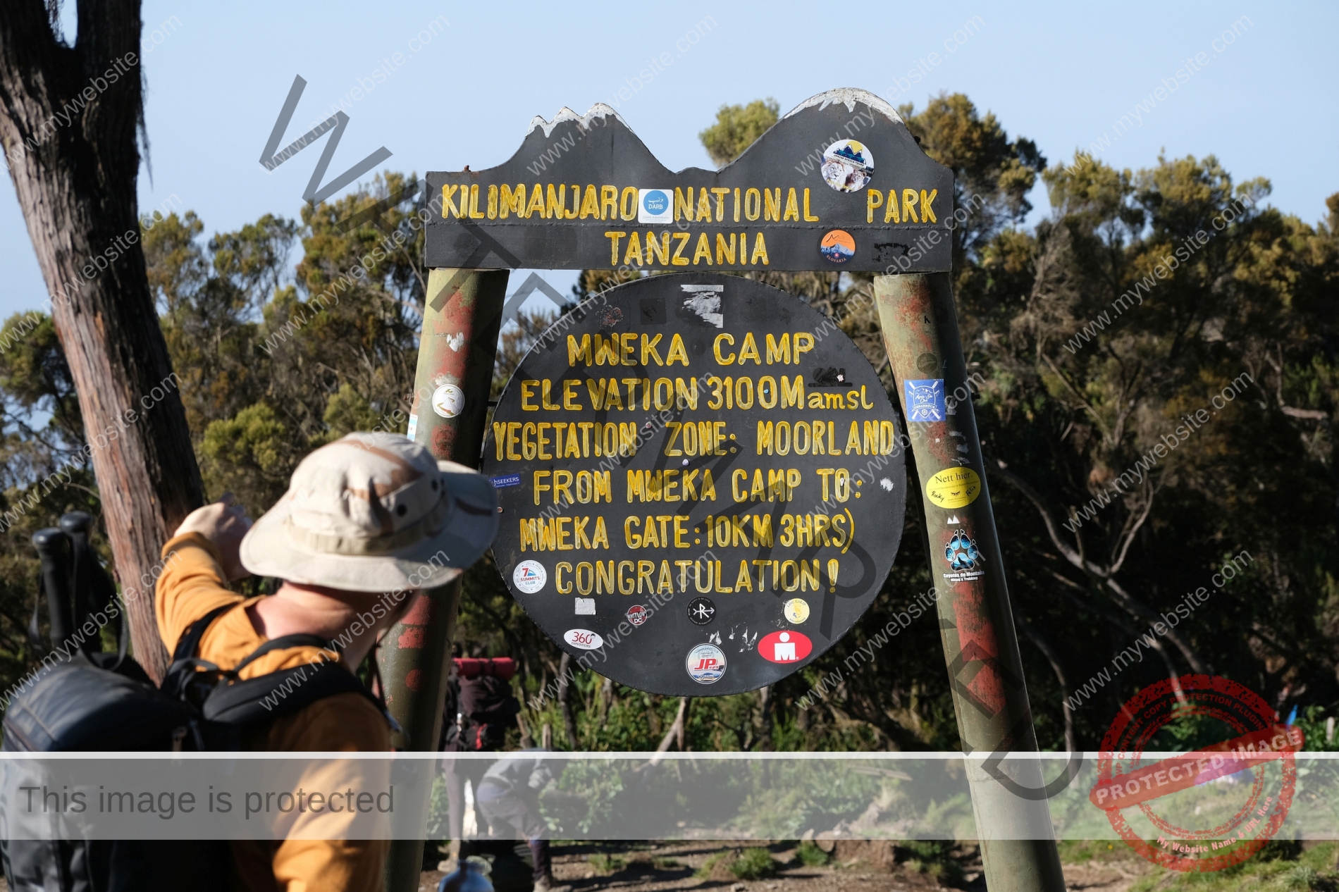 Board information of Machame Gate and silhouette of tourist with backpack on start of route. Machame Route, Kilimanjaro, Tanzania
